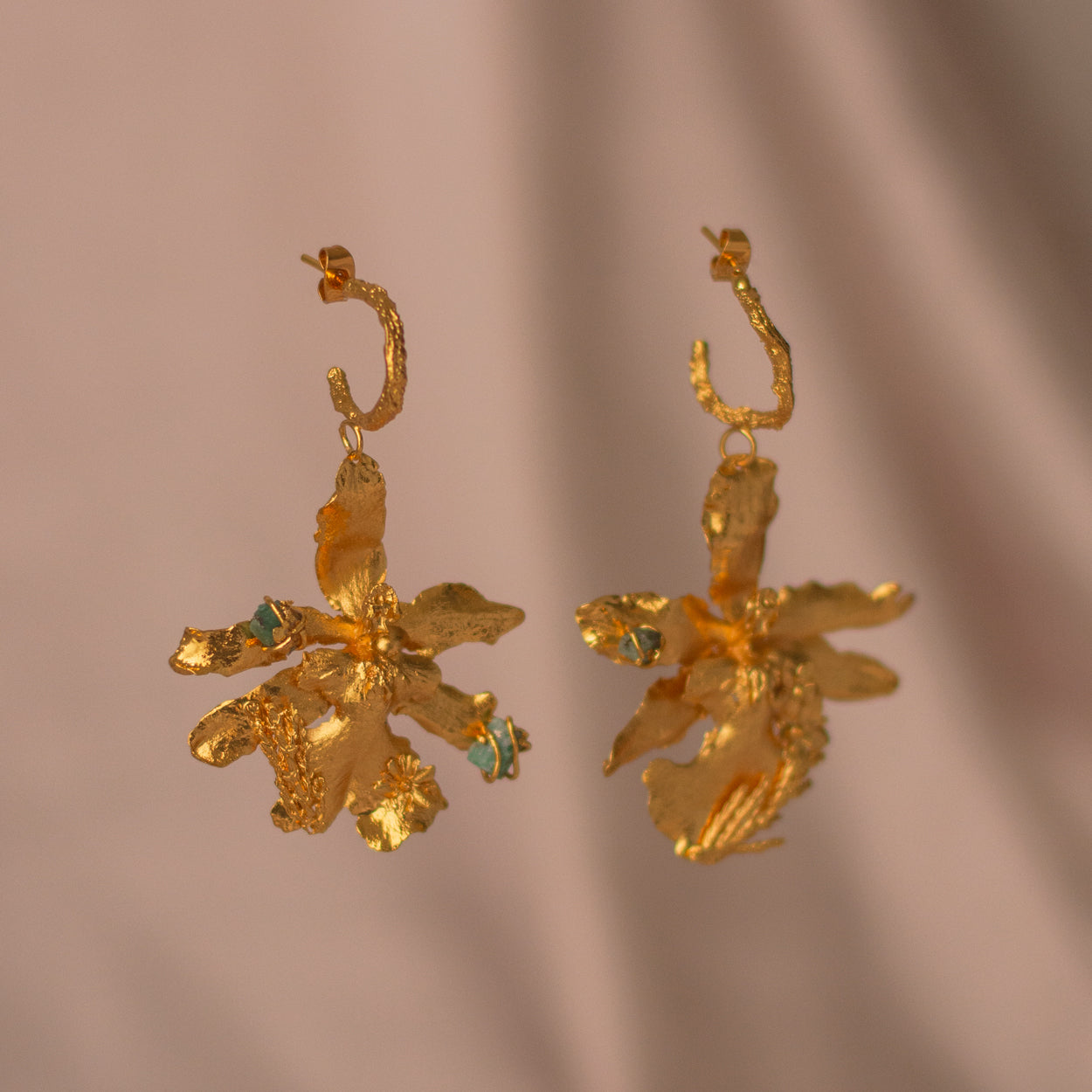 Close-up of Odontoglossum Orchid & Pine Emerald Earrings, featuring bronze and 24k gold plating.