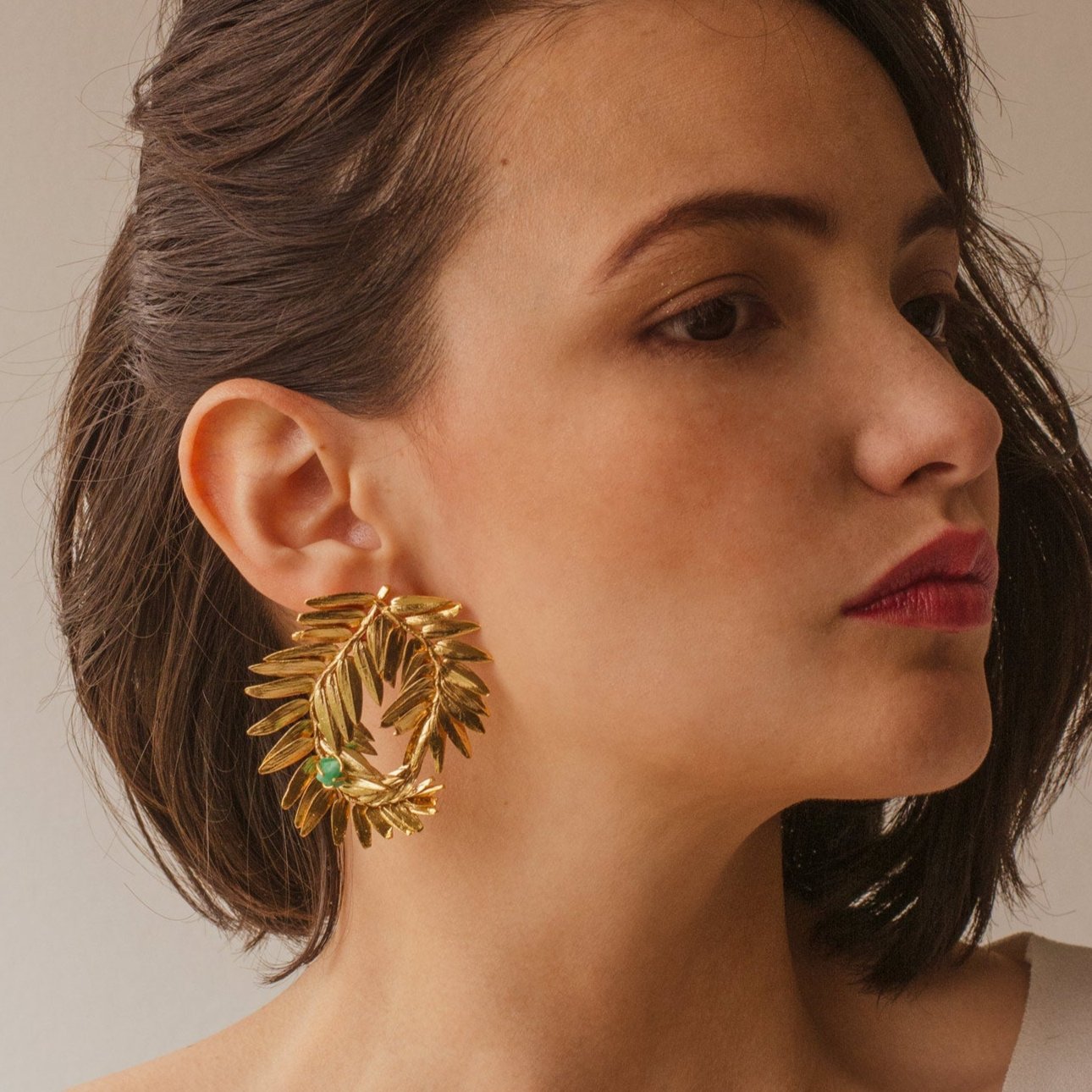 Model wearing Romeron Pine & Emerald Earrings, displaying the spiral design and natural elegance.