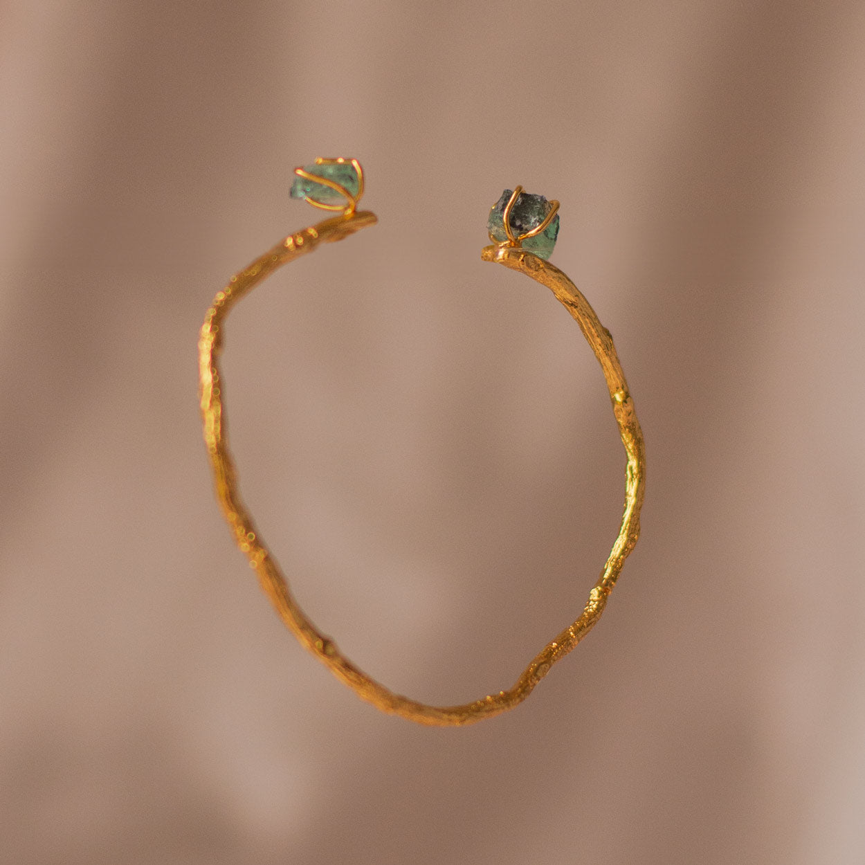 Close-up of Emerald Palm Twig Bracelet with natural coconut palm twigs and 24k gold plating, accented with Colombian emeralds