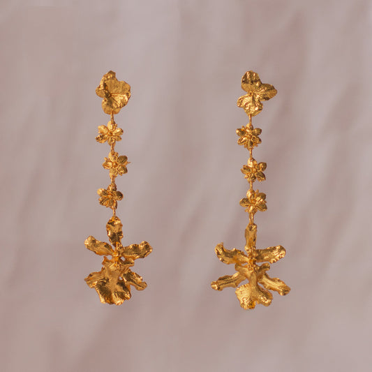 Aretes Orquídea Chocolate Hortensia Sauco en bronce bañado en oro de 24k, destacando la fusión de tres flores naturales inmortalizadas.