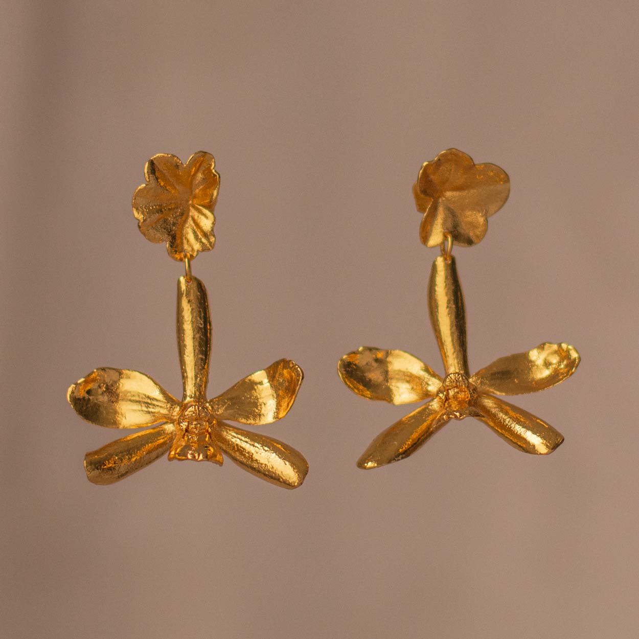 P Crassilabia Orchid Ivy Leaf Earrings lying on a white fabric, highlighting the natural textures and golden shine