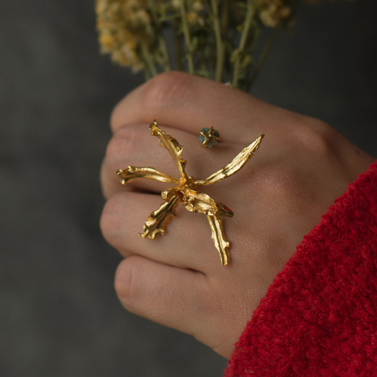 Close-up of Orchid and Emerald Ring, highlighting the intricate orchid design with twig texture.
