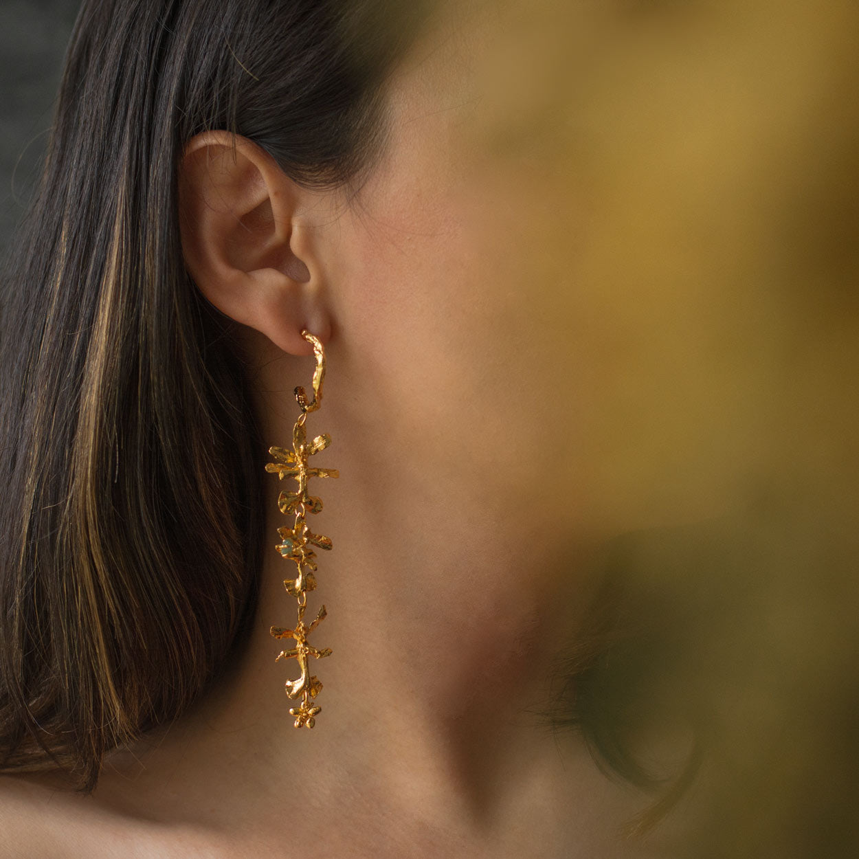 Close-up of Three Oncidium Orchid Emerald Hoops, showcasing the intricate design of orchid flowers and palm twigs with 24k gold plating.