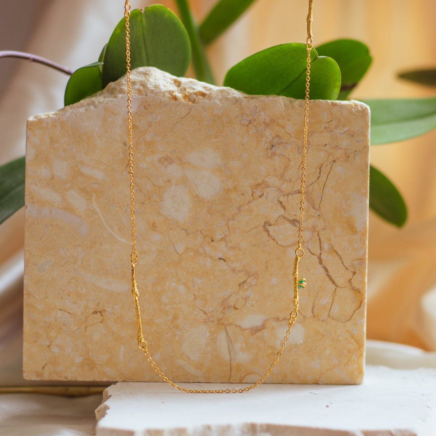 Collar Ramitas Eucalipto Esmeraldas en bronce bañado en oro de 24k, destacando las delicadas ramitas y la brillante morralla de esmeraldas.