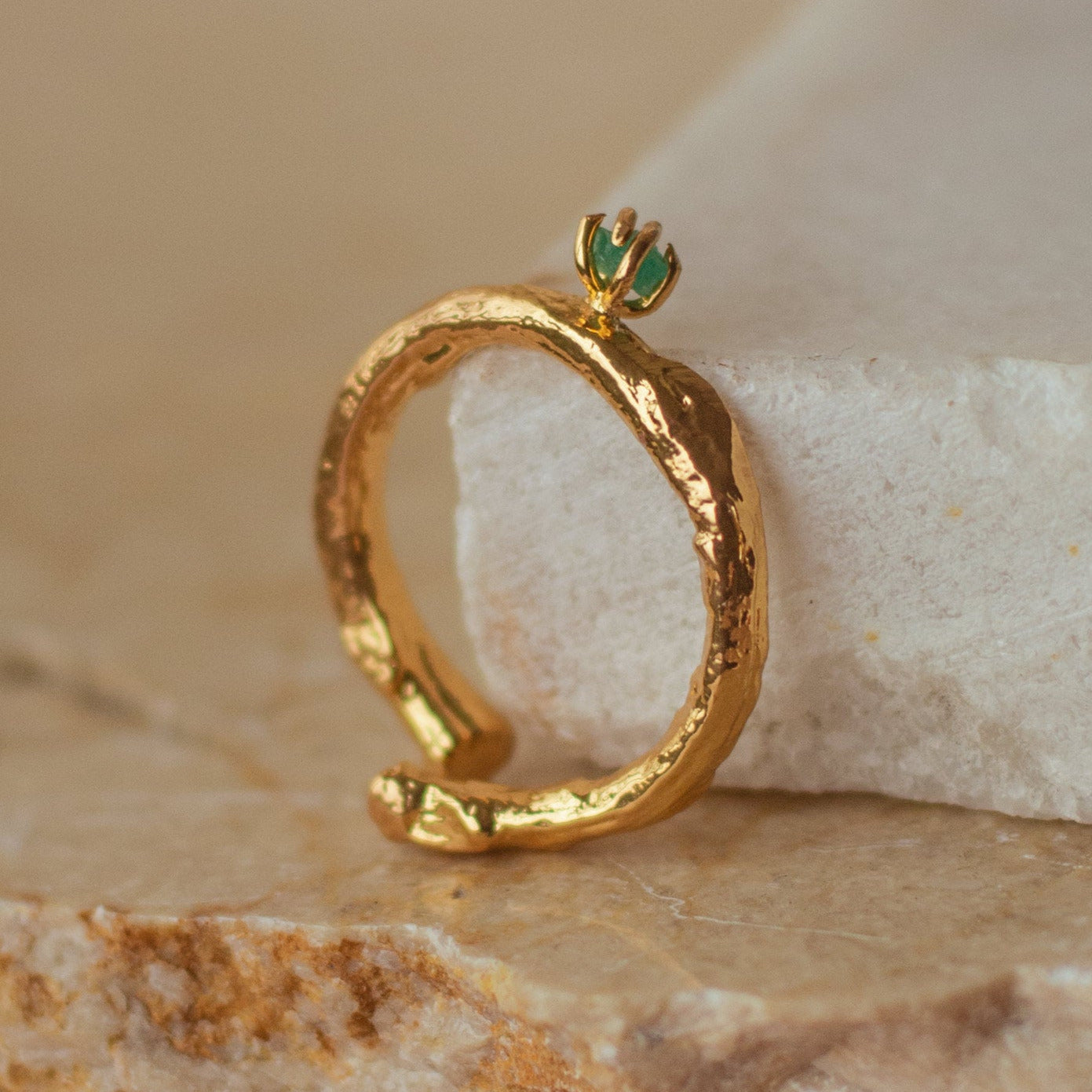 Anillo Ramita con Esmeralda en bronce bañado en oro de 24k, destacando la textura natural de la ramita y el brillante verde de la esmeralda