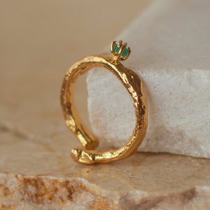 Anillo Ramita con Esmeralda en bronce bañado en oro de 24k, destacando la textura natural de la ramita y el brillante verde de la esmeralda