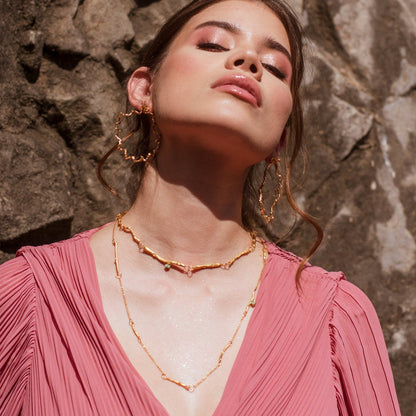 Collar Ramitas Eucalipto Esmeraldas en bronce bañado en oro de 24k, destacando las delicadas ramitas y la brillante morralla de esmeraldas.