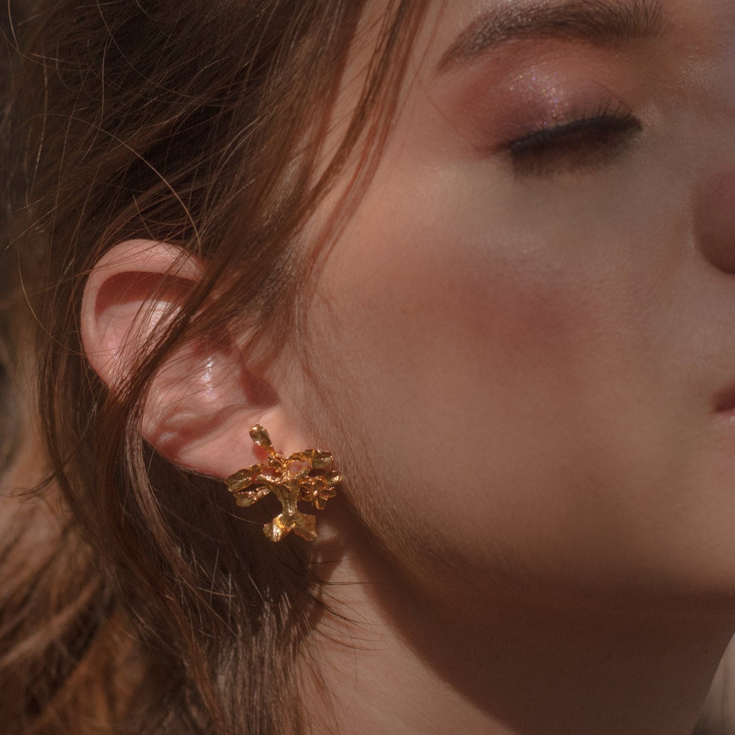 Aretes Topo Orquídea Oncidium en bronce bañado en oro de 24k, mostrando la delicada belleza de la orquídea natural preservada en metal precioso.