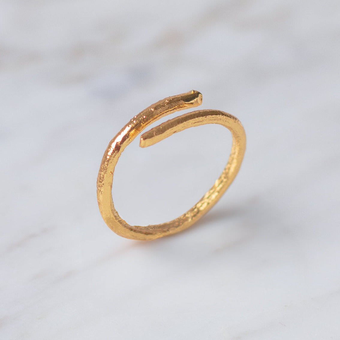 Anillo Ramita en bronce bañado en oro de 24k, destacando la textura y forma única de la ramita natural.