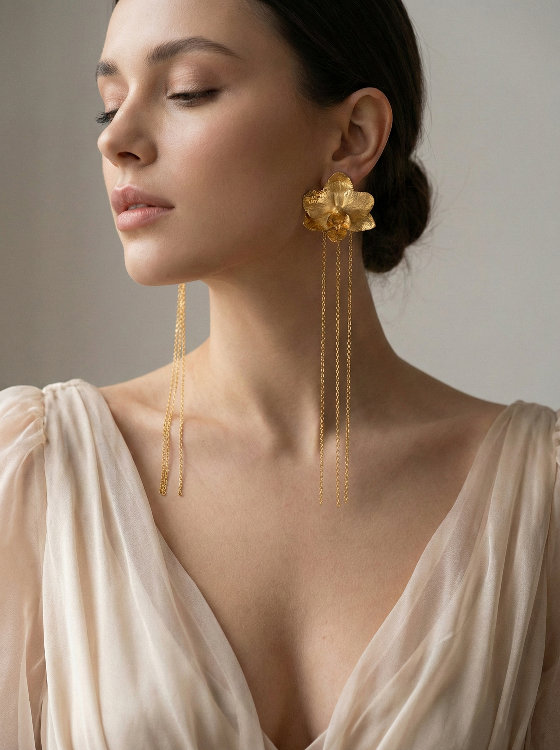 Aretes largos de orquídea real metalizada en bronce con baño de oro y cadena, diseño artesanal colombiano.