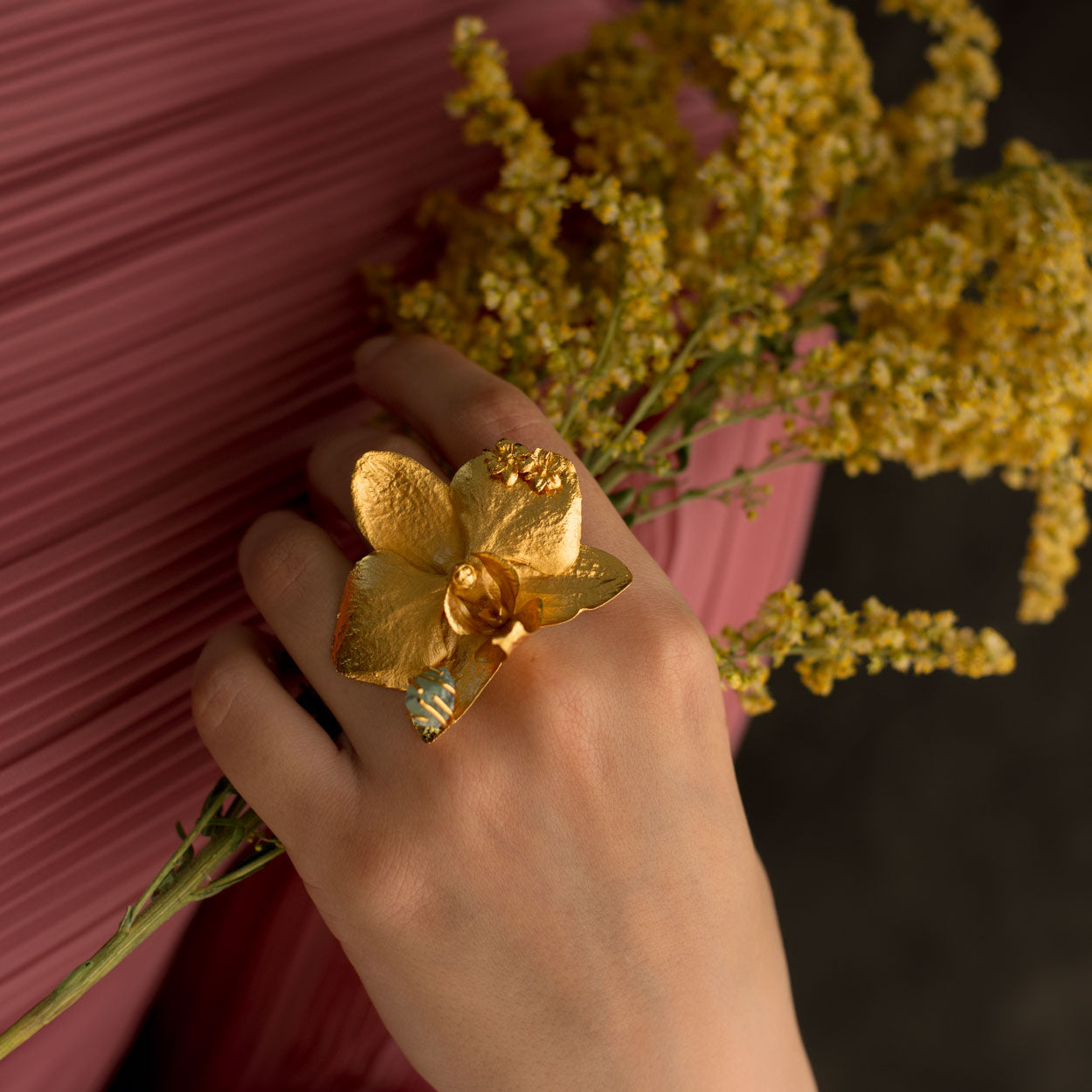 Hand wearing the Phalaenopsis Orchid Elderflower Emerald Ring, highlighting its unique floral design and sparkling emerald