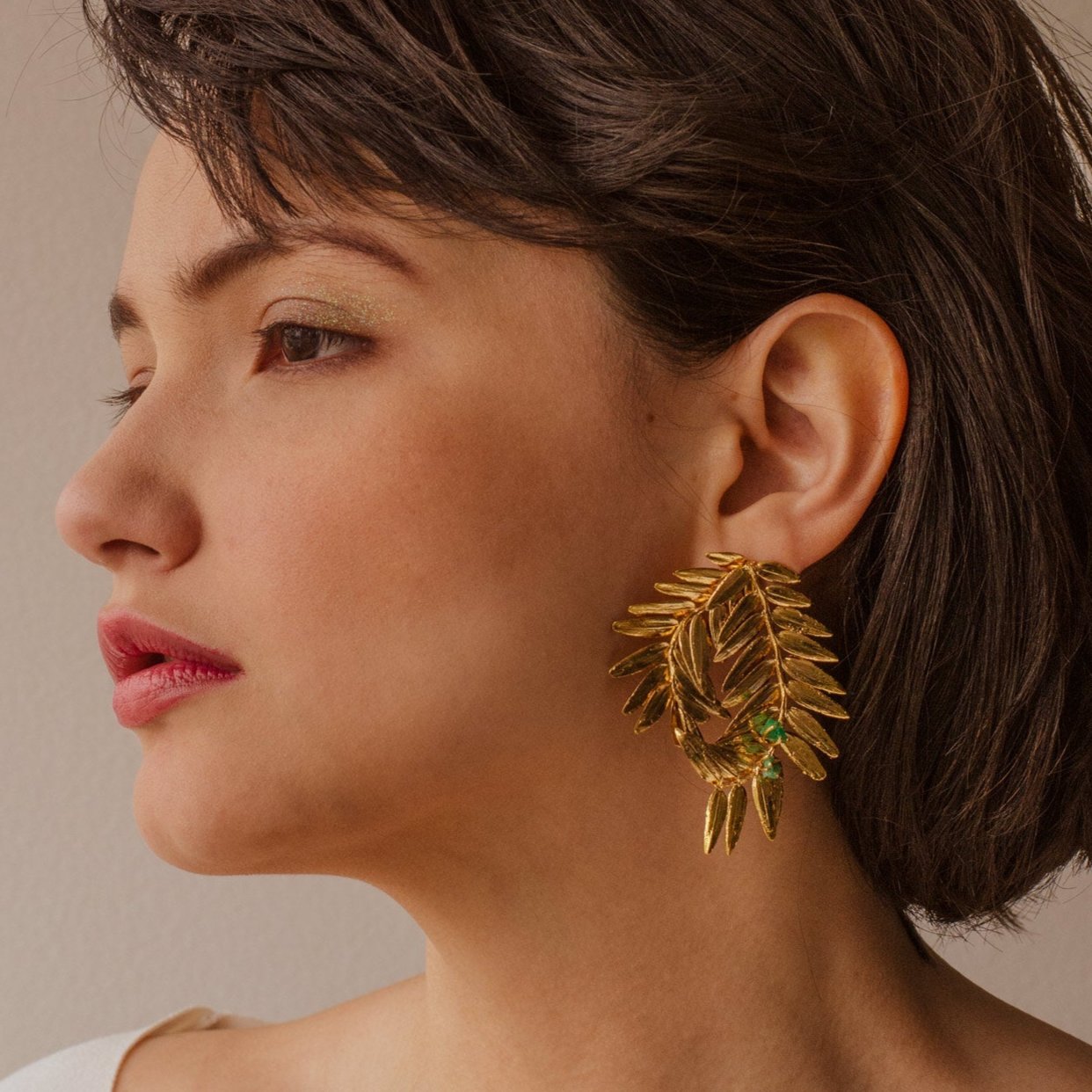 Model wearing Romeron Pine & Emerald Earrings, displaying the spiral design and natural elegance.
