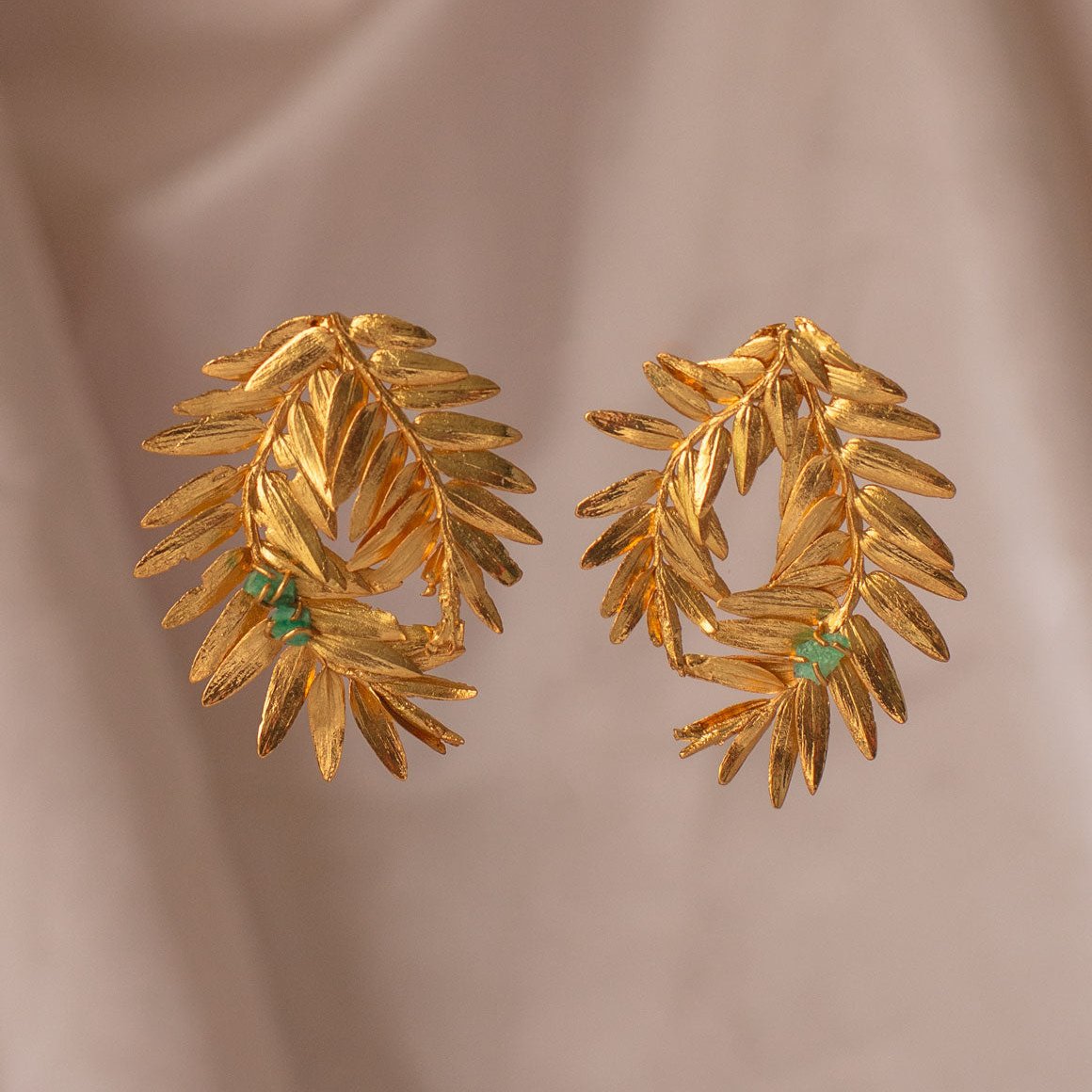 Romeron Pine Spiral & Emerald Earrings with 24k gold-plated leaves and raw Colombian emeralds.
